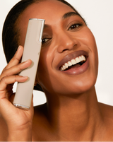 DERMAFLASH LUXE+ - Stone | Model holding LUXE+ dermaplaning device in Stone near her face