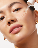 LUXE+ AND SERUM SET - Rose Gold | Image of model applying Active Cocooning Serum on her cheek