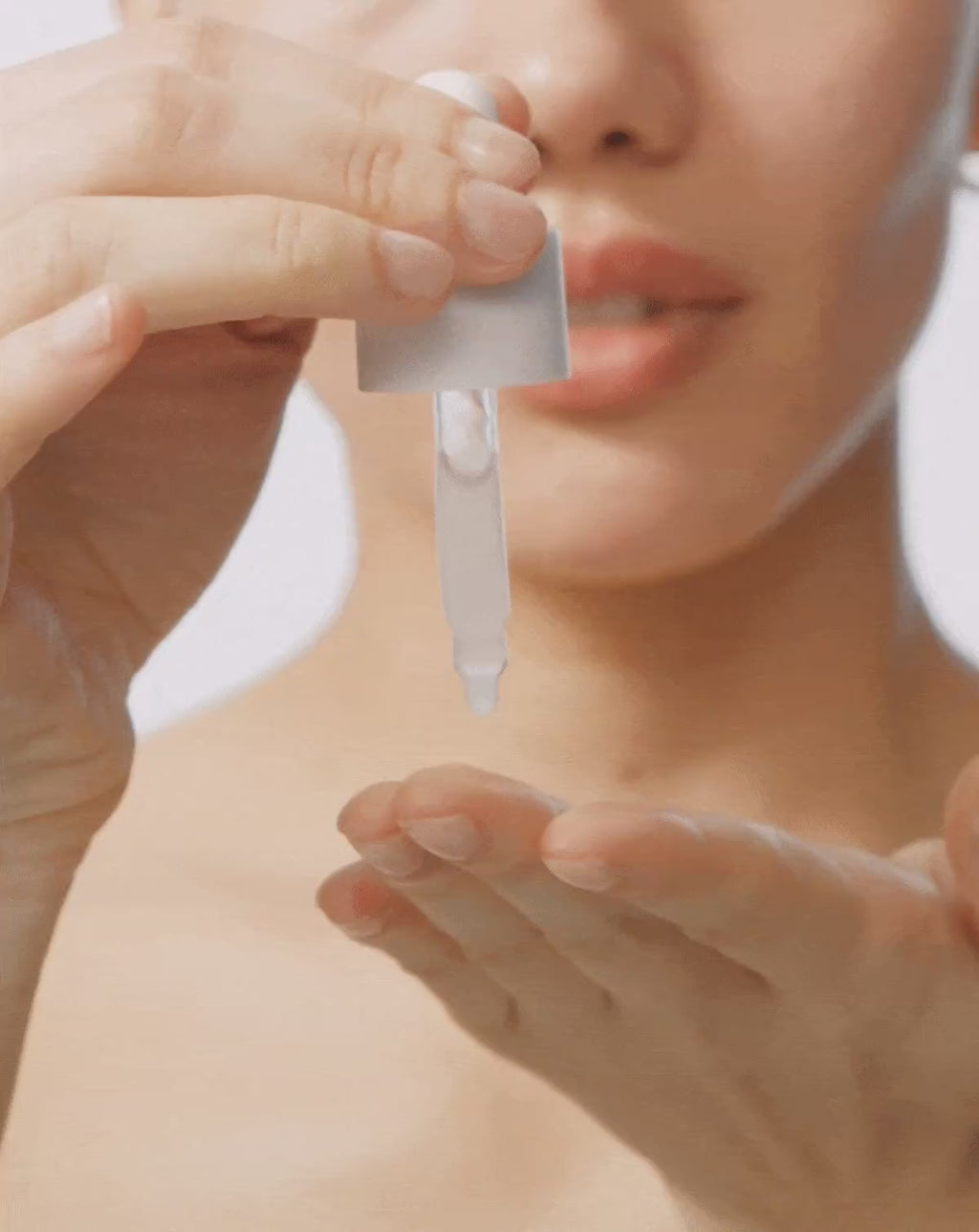 Model dispensing ACTIVE COCOONING SERUM from dropper and applying to her face 
