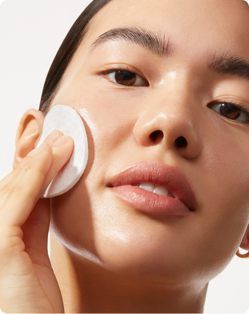 Model applying BOTANICAL KETOACID TONER to her face with a cotton pad 