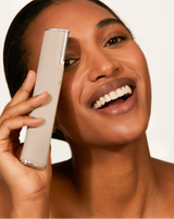DERMAFLASH LUXE+ - Stone | Model holding LUXE+ dermaplaning device in Stone near her face 
